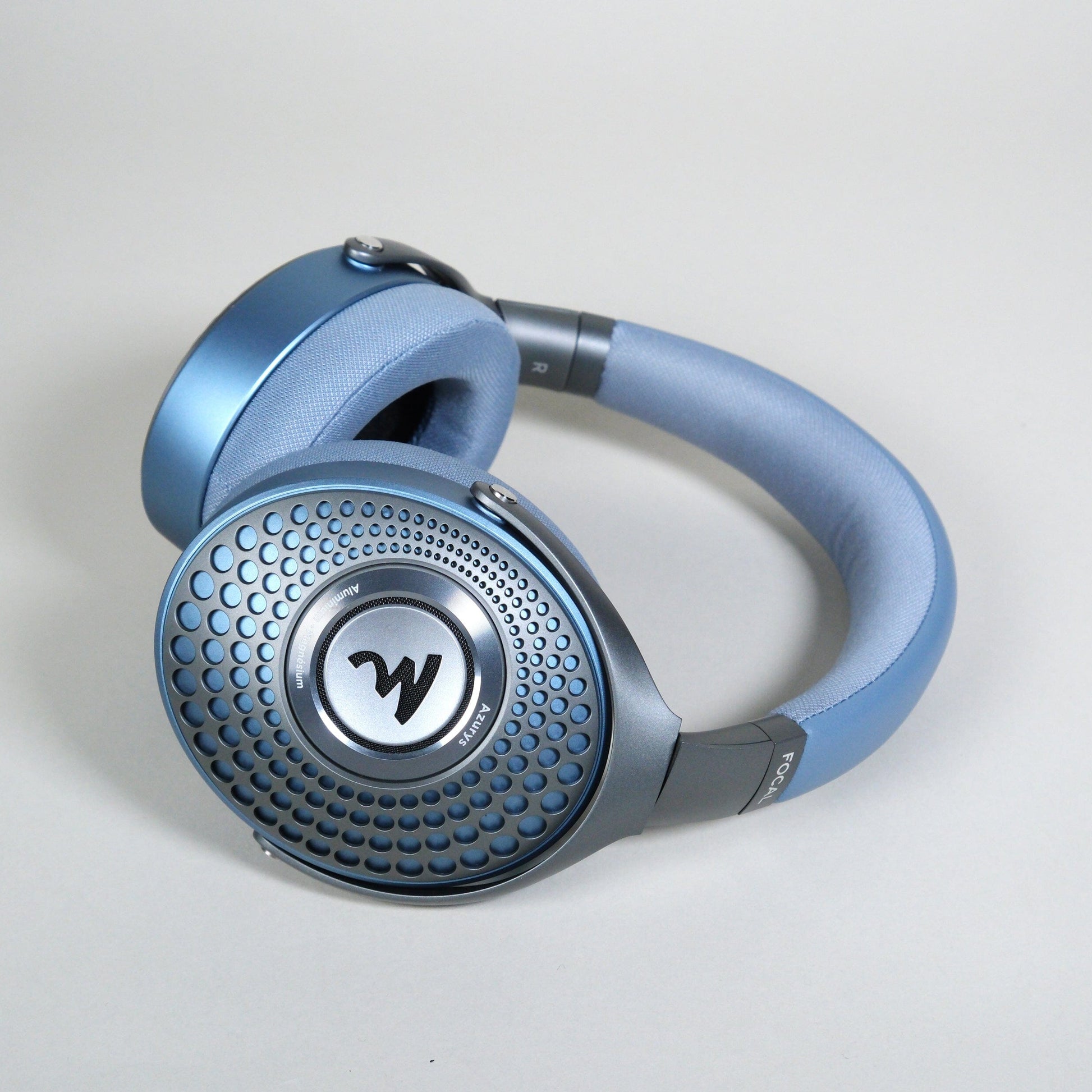 Focal Azurys blue over-ear headphones by Focal feature a textured circular ear cup design with a central W logo, shown against a plain light gray background.
