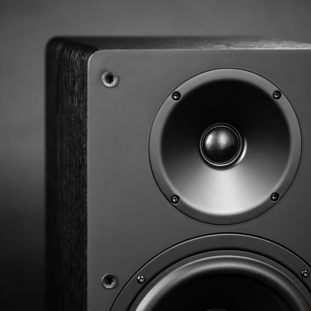Close-up of the ELAC DCB61 Debut ConneX 2-Way Active Wireless Bookshelf Speaker, showcasing its modern black design with visible woofer and tweeter, by ELAC, set against a blurred gray background.