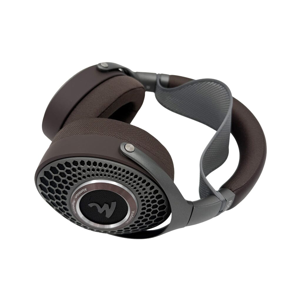 A pair of over-ear, open-back headphones with a brown and gray color scheme features a honeycomb grille and the Capra Comfort Strap for Focal Headphones (Small) by Capra Audio, shown on a white background.