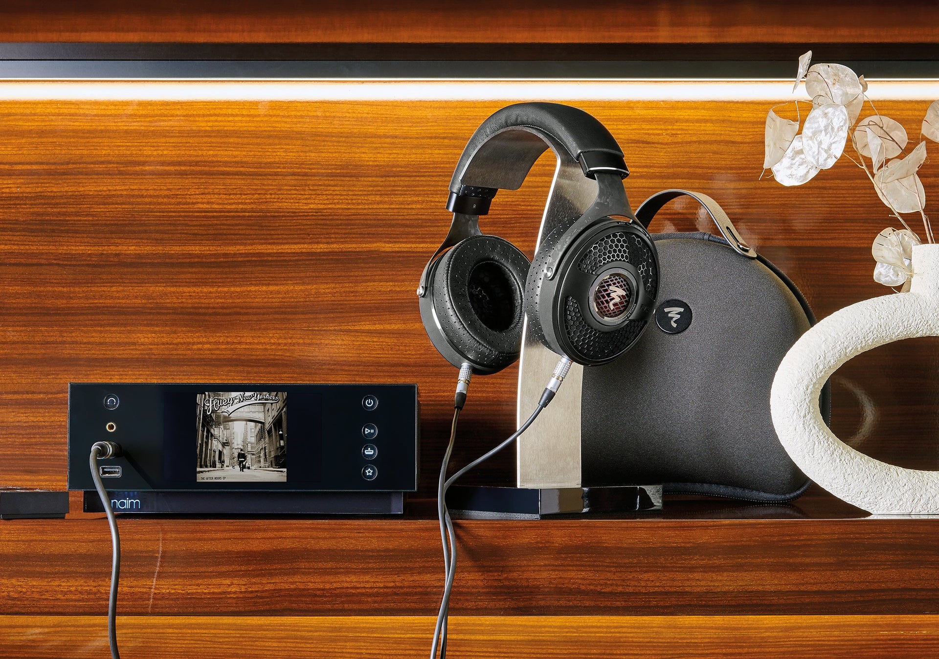 Utopia headphones on stand connected to Naim amplifier on wood backdrop