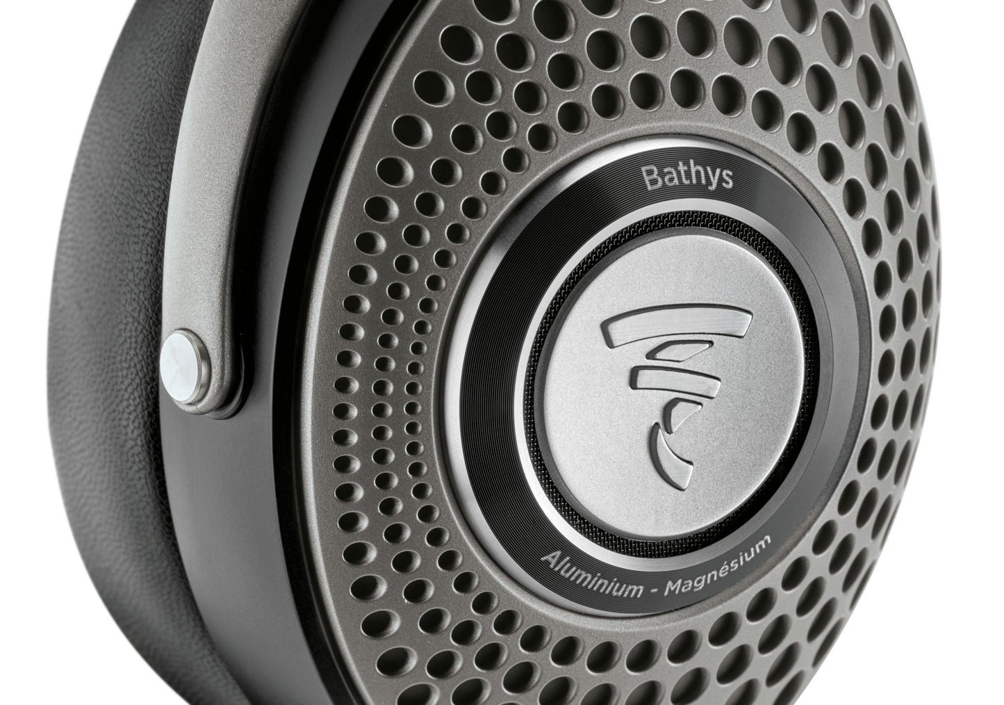 Close-up of the Focal Bathys headphone ear cup by Focal, featuring a perforated metallic grille with the Focal logo, and “Bathys” plus “Aluminium - Magnesium” engraved around it.