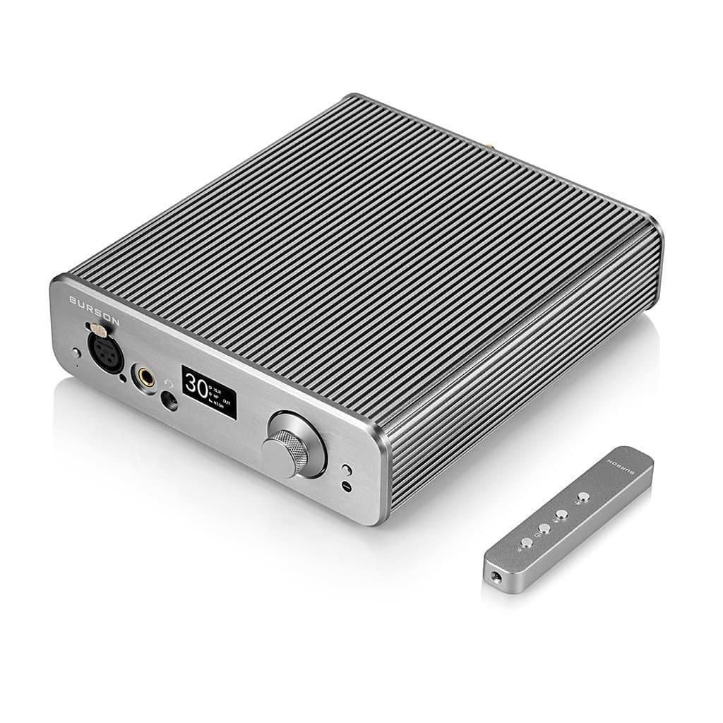 A silver Burson Audio Soloist 3X Performance amplifier with a ridged metal exterior, Max Current Power Supplies, multiple ports, a display reading 30, and a round knob is next to a slim three-button remote control.