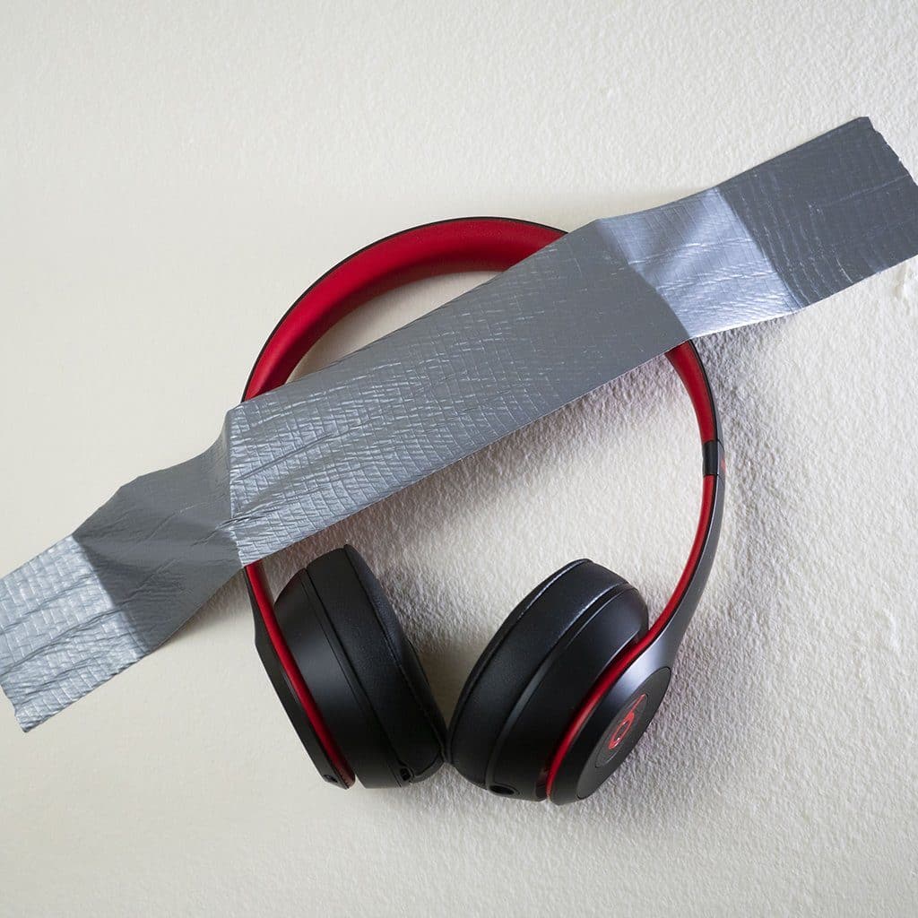 A pair of Mediocre Headphones on Wall from headphones.com—black and red, taped to a white wall with silver duct tape—isnt what youd expect from headphones.com.