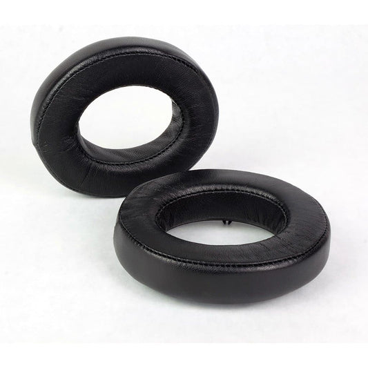 Two black oval Dekoni Audio Elite Sheepskin Ear Pads for Focal headphones, compatible with Utopia, are shown—one upright and one flat on a white background.