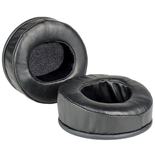 Two black, round Dekoni Audio Elite Sheepskin Ear Pads for Audeze LCD Series are shown, featuring soft memory foam and a leather-like sheepskin surface; one stands upright while the other lies flat to display the inner cushion.