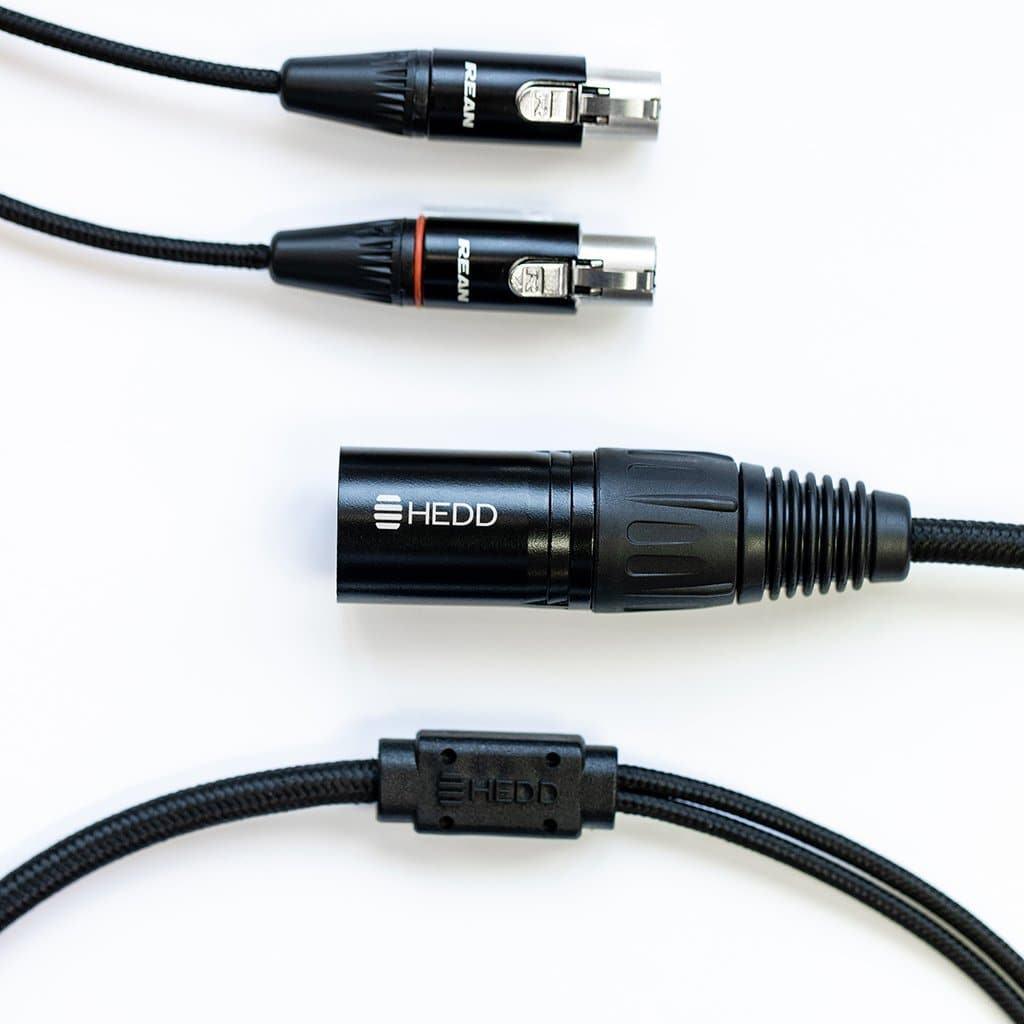 The HEDD Audio HEDDphone Balanced 4-Pin XLR Cable features black connectors, including XLR plugs and sockets with the HEDD logo, perfect for connecting the HEDDphone to a headphone amplifier. Shown on a white background.