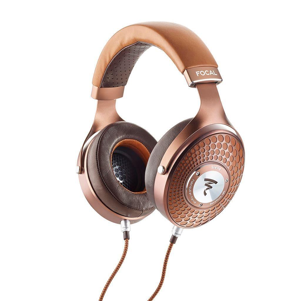 The Focal Stellia Headphones are stylish, closed-back headphones in bronze and brown tones, featuring a padded headband with visible Focal branding, textured ear cups, and an attached braided audio cable.
