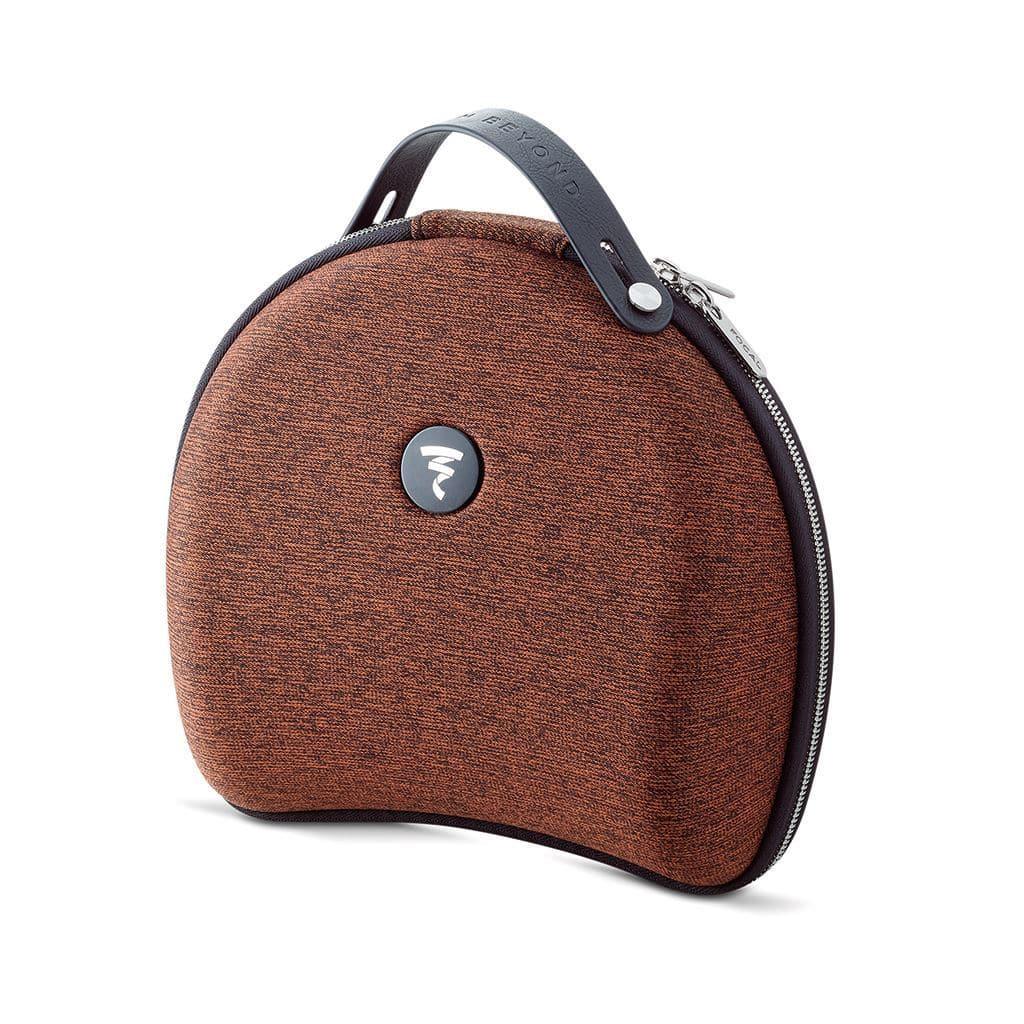 A curved brown carrying case with a textured finish, black top handle, zipper closure, and circular Focal logo in the center. Designed to hold Focal Stellia closed-back headphones upright on a flat surface.