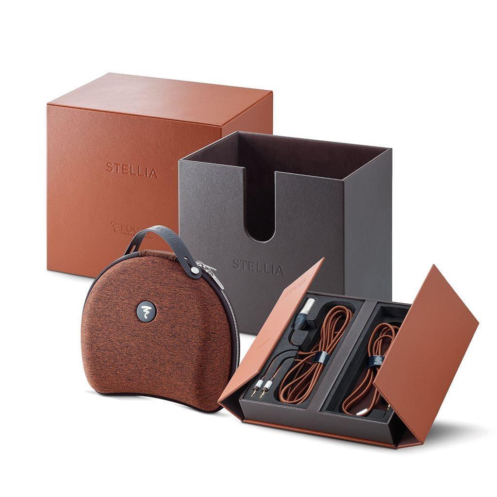 The Focal Stellia Headphones, a luxury closed-back set, feature brown leather with a fabric carrying case, brown-black presentation box, neatly arranged cables in an open tray, and highlight the Focal brand and Beryllium dome driver on the packaging.