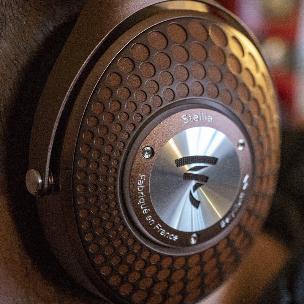 Close-up of a brown Focal Stellia Headphones ear cup by Focal, showing its textured circular pattern and engraved metal plate, designed for superior sound isolation.