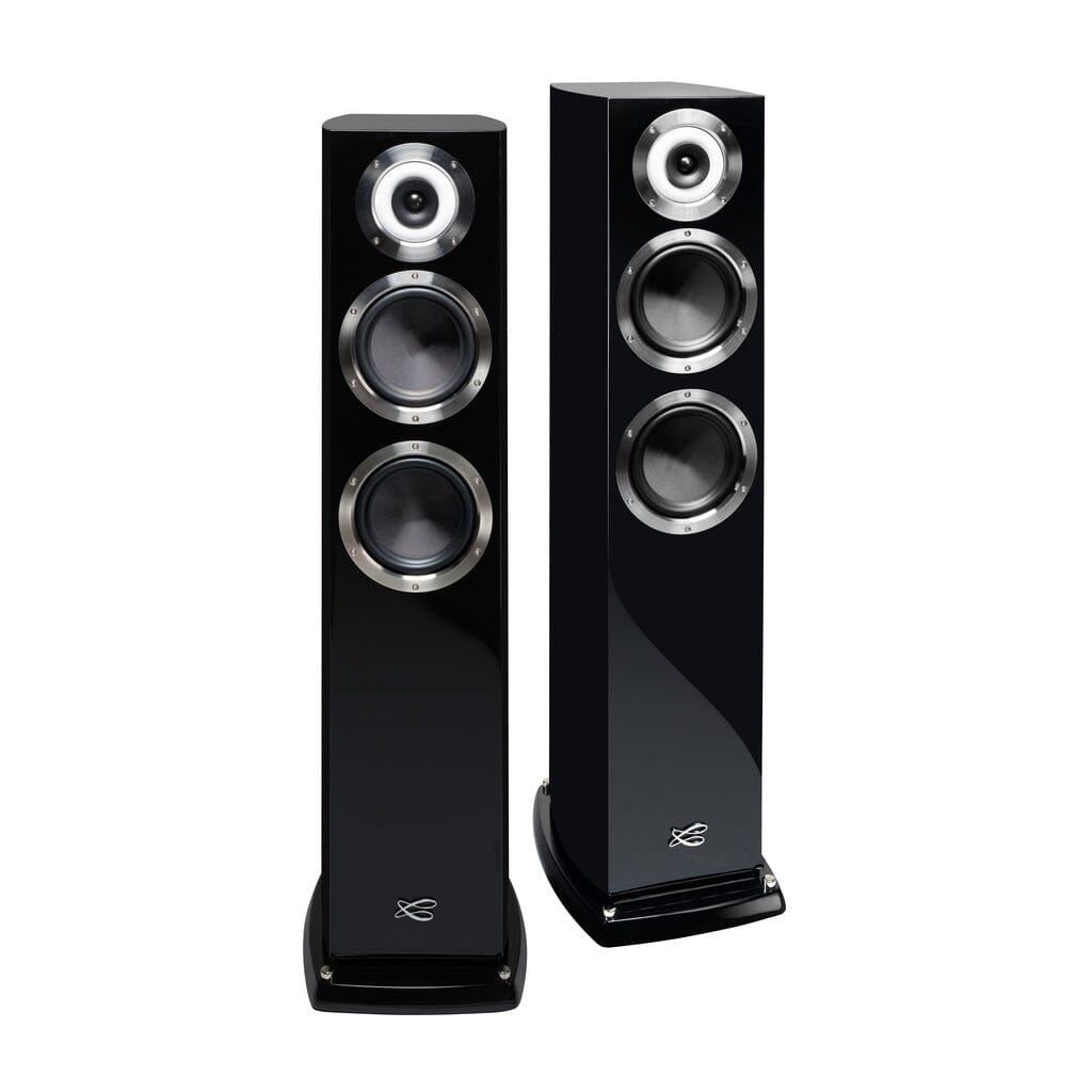 Two tall, black Cabasse MURANO ALTO floorstanding speakers, each with three circular drivers and a coaxial tweeter-midrange on the glossy front, are positioned side by side and slightly angled for an authentic high-end stereo experience.