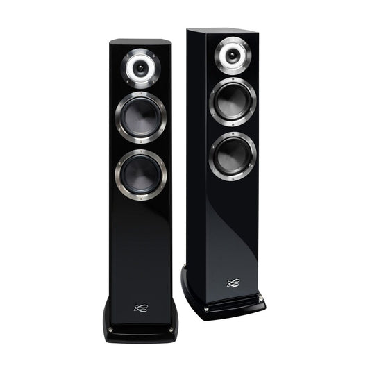 Two tall, black Cabasse MURANO ALTO floorstanding speakers, each with three circular drivers and a coaxial tweeter-midrange on the glossy front, are positioned side by side and slightly angled for an authentic high-end stereo experience.