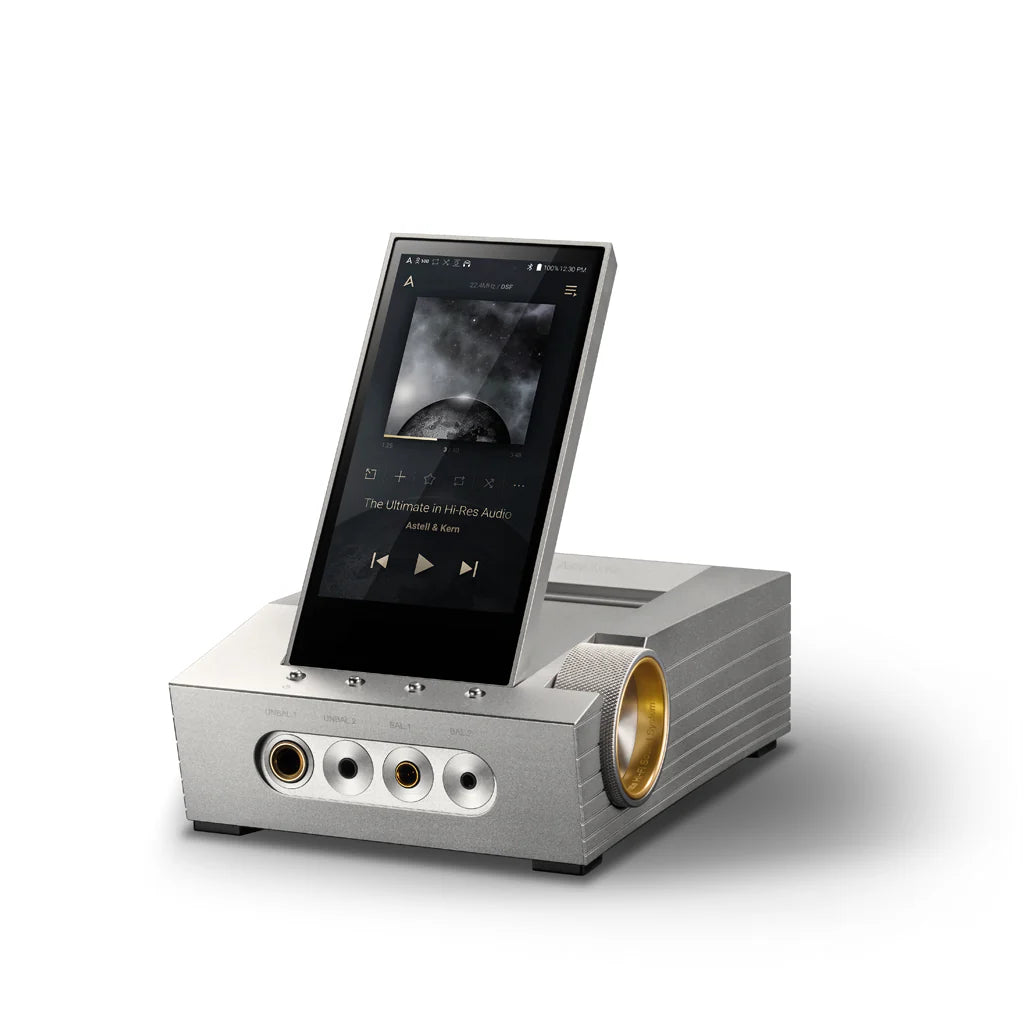 The Astell&Kern CA1000 Headphone Amplifier - Open Box by Astell & Kern features a quad DAC, tilted touchscreen, silver metallic body, gold volume dial, and multiple front audio ports, shown playing music with album art on display.