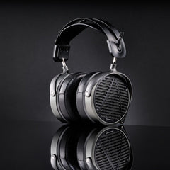 Audeze MM-520 Headphones by Audeze feature a modern, over-ear black design with a metallic frame and mesh earcups, planar magnetic drivers, and are shown on a glossy black surface with their reflection visible. Preview