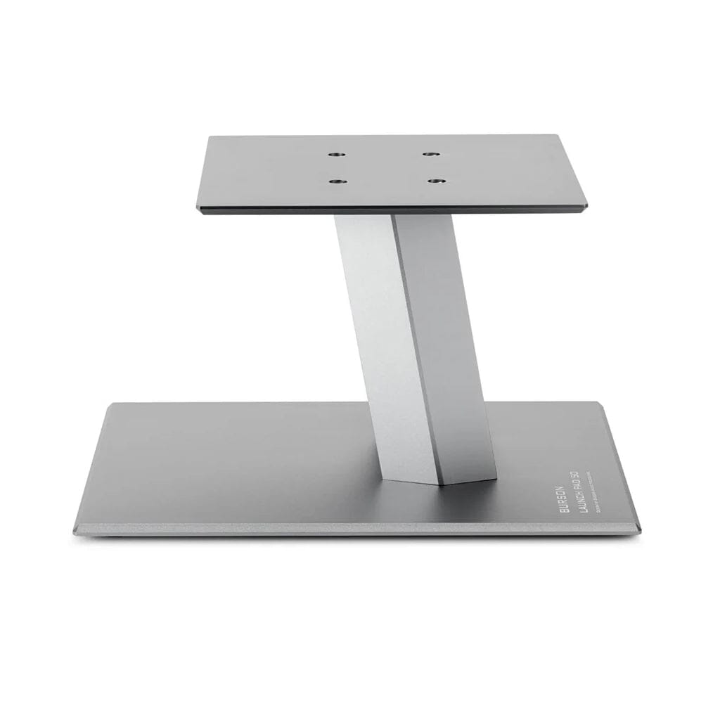 The Burson Audio Launch Pad 50 Desktop Speaker Stands (Pair) from Headphones.com feature a modern silver metal design with a flat base, angled support, and top platform with four mounting holes—perfect for bookshelf speakers.