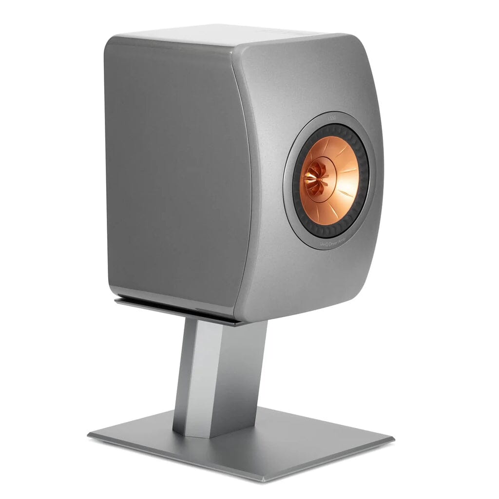 A modern metallic gray bookshelf speaker with a copper driver is placed on a pair of Burson Audio Launch Pad 50 Desktop Speaker Stands from Headphones.com, all set against a crisp white background.