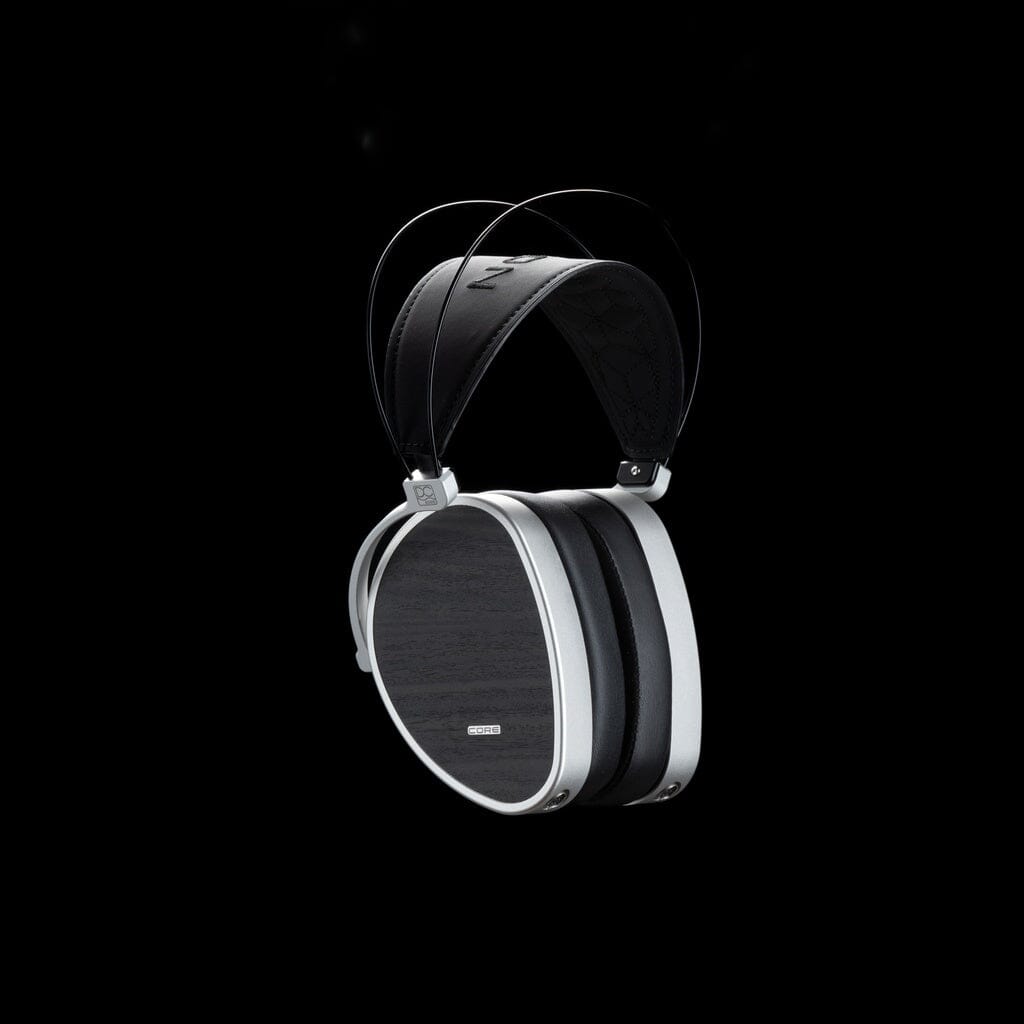 The Dan Clark Audio AEON CORE Headphones feature a black and silver design with a wide headband and circular closed-back ear cups, shown against a black background.