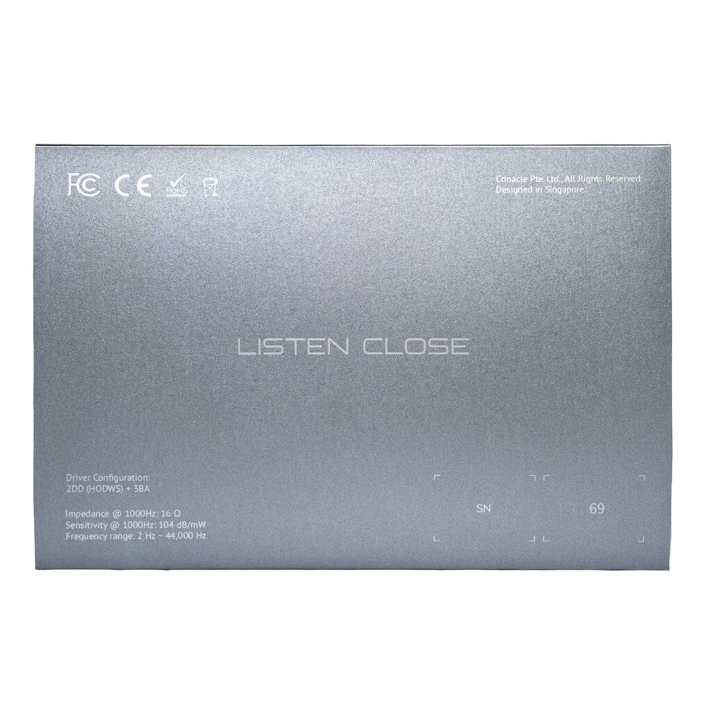 The CrinEar Reference In-Ear Headphones feature "LISTEN CLOSE" at the center, technical specs and certification symbols at the top left. This smooth silver-gray model from CrinEar is designed for tonal accuracy.