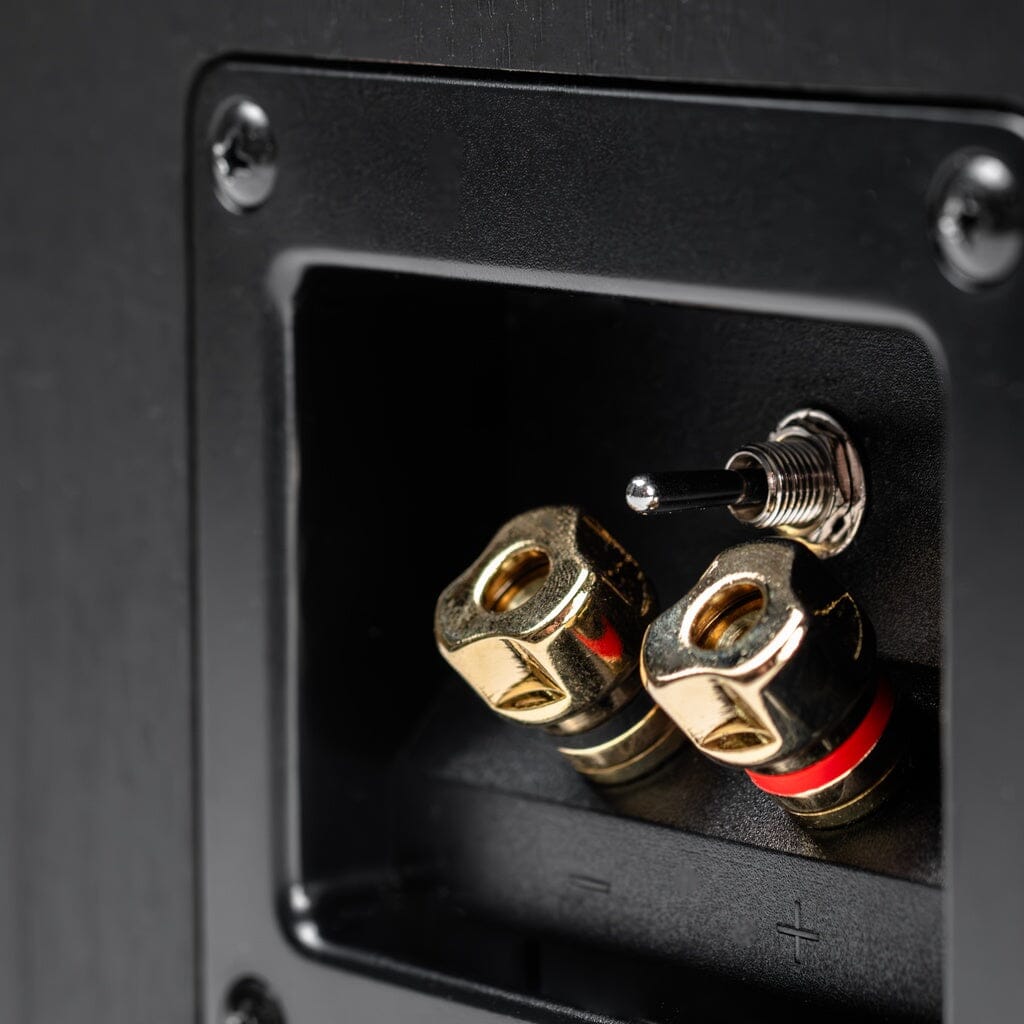 Close-up of the ELAC Debut 3.0 DA43 2-Way Dolby Atmos Speaker terminal panel with gold binding posts (red/black) and a toggle switch in a black recess—perfect for elevating your home theater setup.
