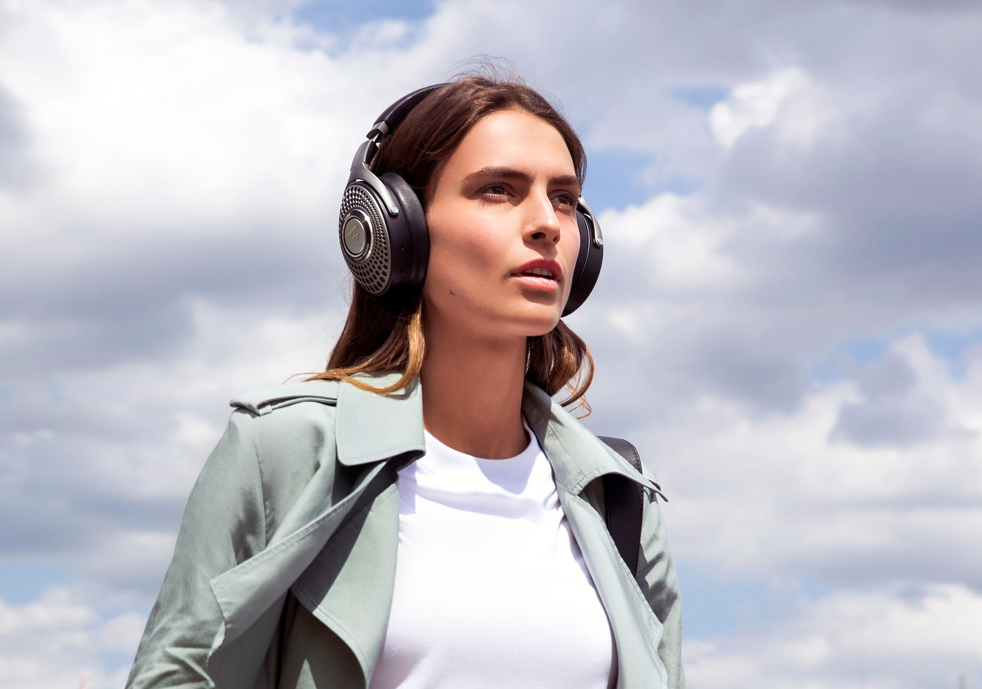 Woman wearing Focal Bathys wireless noise-cancelling headphones outside on a cloudy day