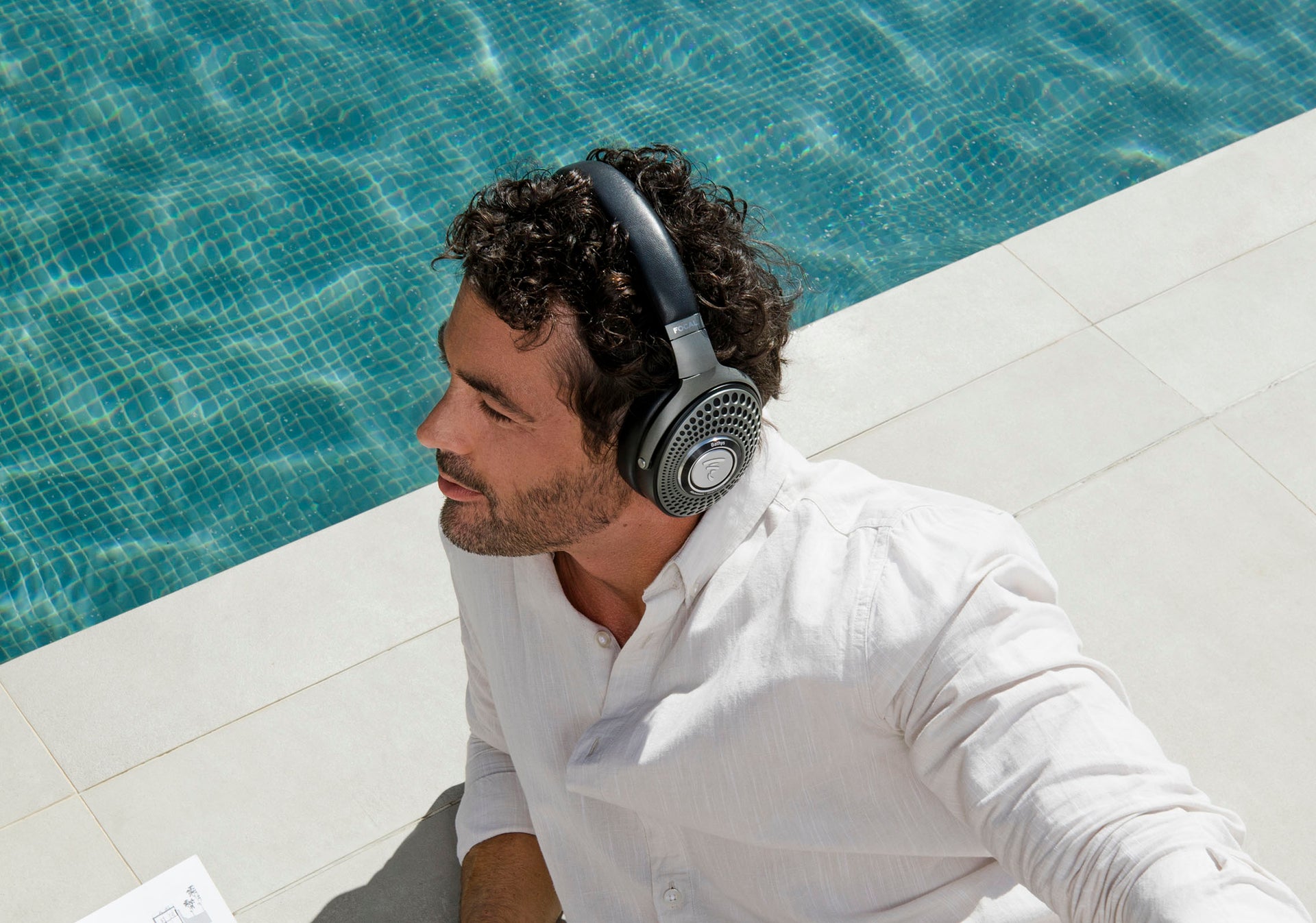 Man listenting to Focal Bathys wirless ANC headphone near pool