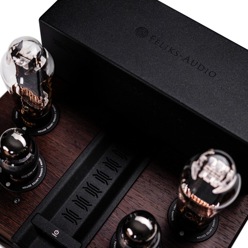 Close-up of the Feliks Audio Envy Susvara Edition headphone amplifier with four vacuum tubes, a black casing on a dark wood base, and the Feliks Audio logo on top.