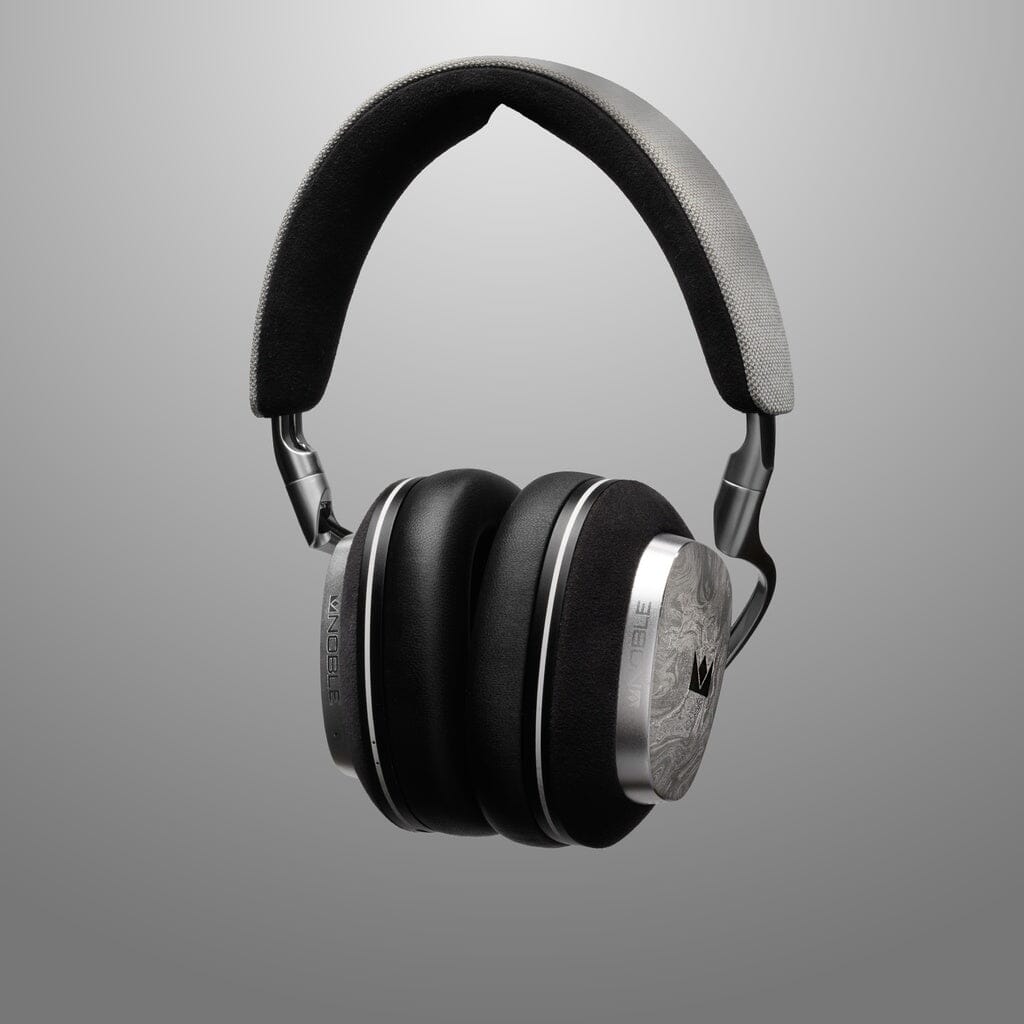 The Noble Audio FoKus Artemis Wireless Headphones by Noble Audio feature a black over-ear design with a padded headband, metallic earcup accents, and active noise cancellation, shown against a smooth gray background.