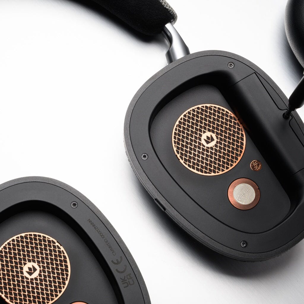 Close-up of Noble Audio FoKus Artemis Wireless Headphones by Noble Audio, featuring black and gold mesh grilles, detailed branding on inner ear cups, and hybrid three-driver tech—all set against a white background.