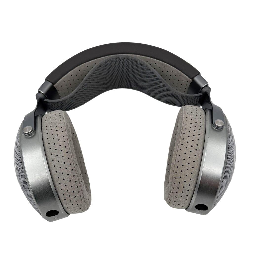 The Focal Clear Headphones + Capra Strap Comfort Bundle features Focal's silver over-ear headphones with grey perforated cushions and a padded black headband, paired with the Capra Comfort Strap, all displayed against a white background.