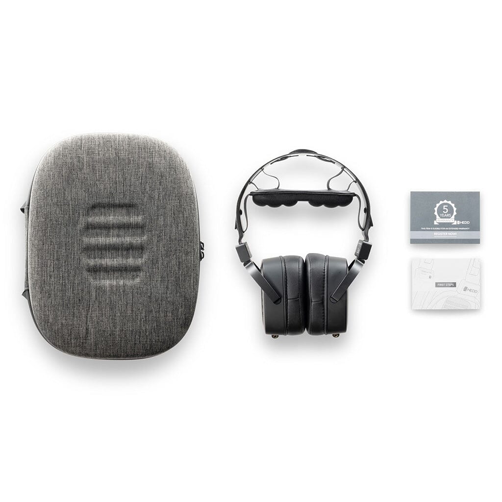 A grey carrying case, black HEDD Audio HEDDphone TWO GT UNPLUGGED Edition over-ear headphones with AMT driver, a warranty card, and a white manual are displayed on a white background.