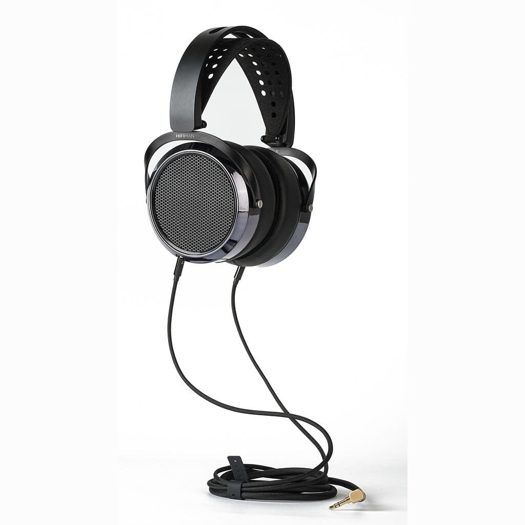 A pair of Hifiman HE6 Remastered open-back headphones, featuring a perforated headband and a long coiled cable with a gold-plated plug, is displayed on a white background.