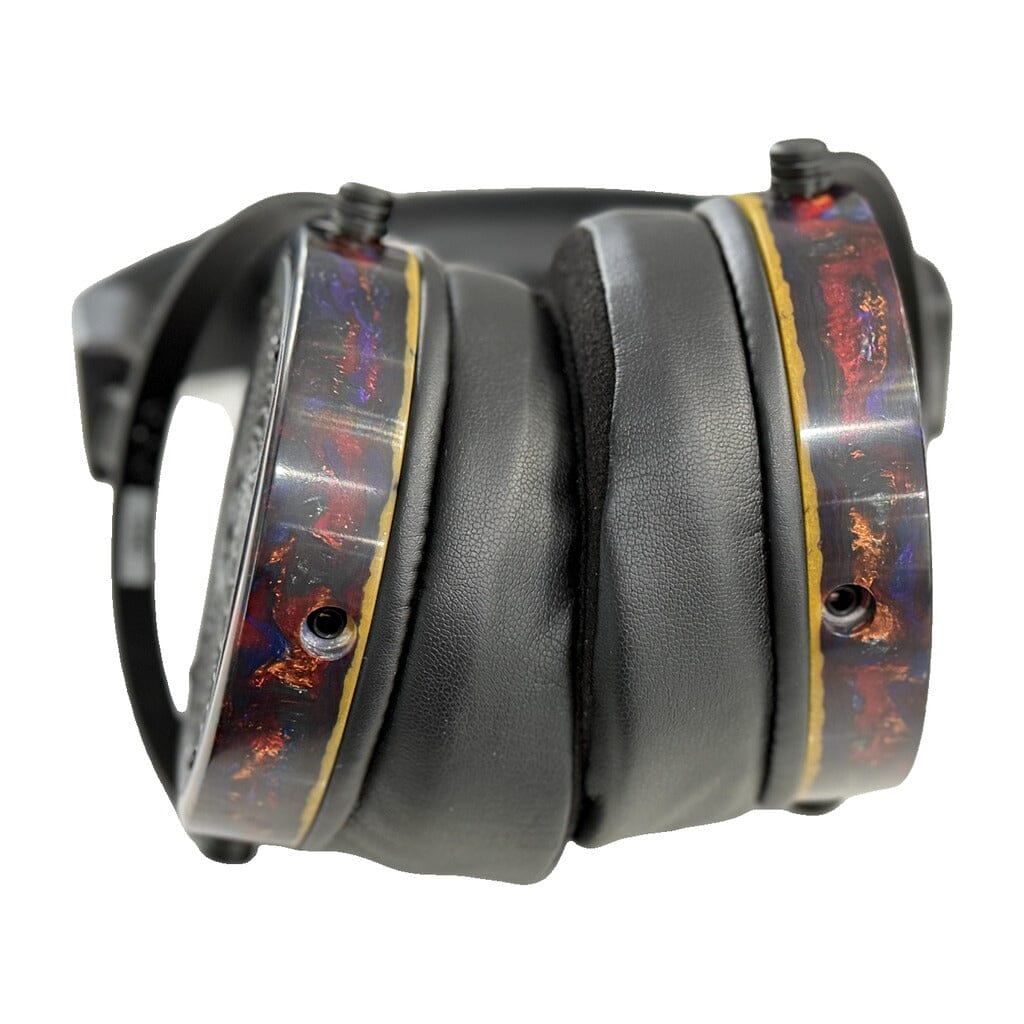 A close-up of open box Rosson Audio Design RAD-0 headphones, showcasing black leather ear pads and vibrant, marbled ear cups with gold and red accents.