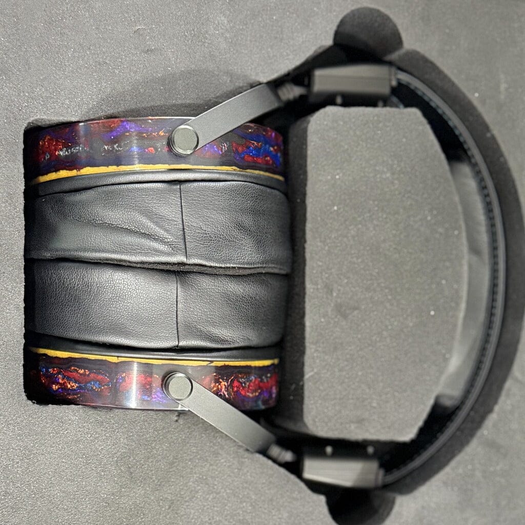 An open box pair of Rosson Audio Design RAD-0 Headphones features luxurious black leather ear pads and vibrant, marbled side accents. Presented securely in a foam-lined carrying case, this clearance set from Rosson Audio Design blends eye-catching aesthetics with exceptional sound engineering.
