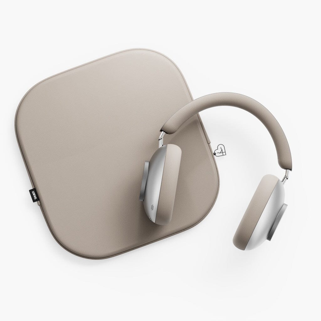 A pair of Loewe Leo Wireless Headphones in beige and silver rests on a matching beige square mat, both placed against a white background.
