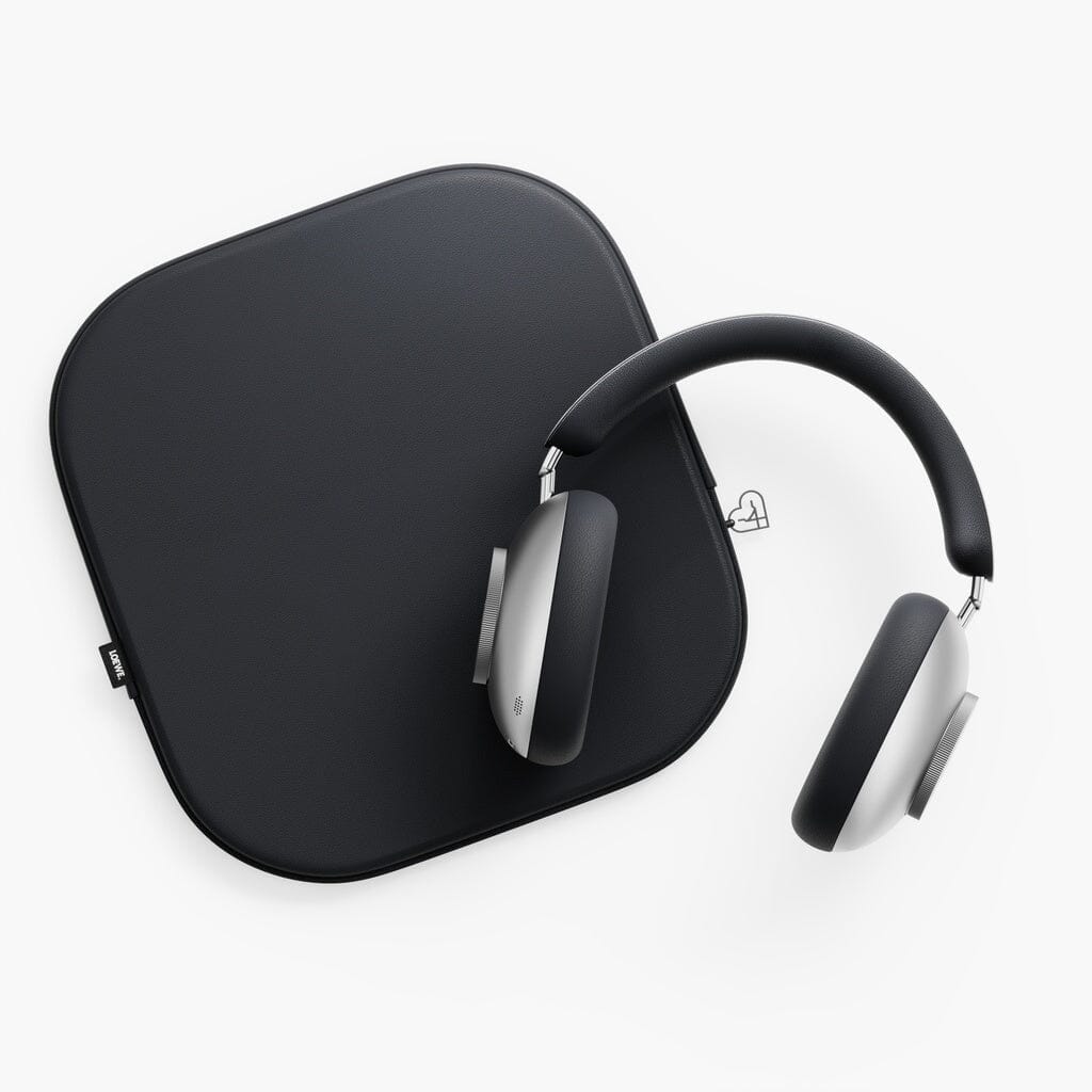 The Loewe Leo Wireless Headphones by Loewe, featuring a sleek black and silver design, rest on a flat, square black case against a white background, offering personalized sound and adaptive noise cancellation for an elevated listening experience.