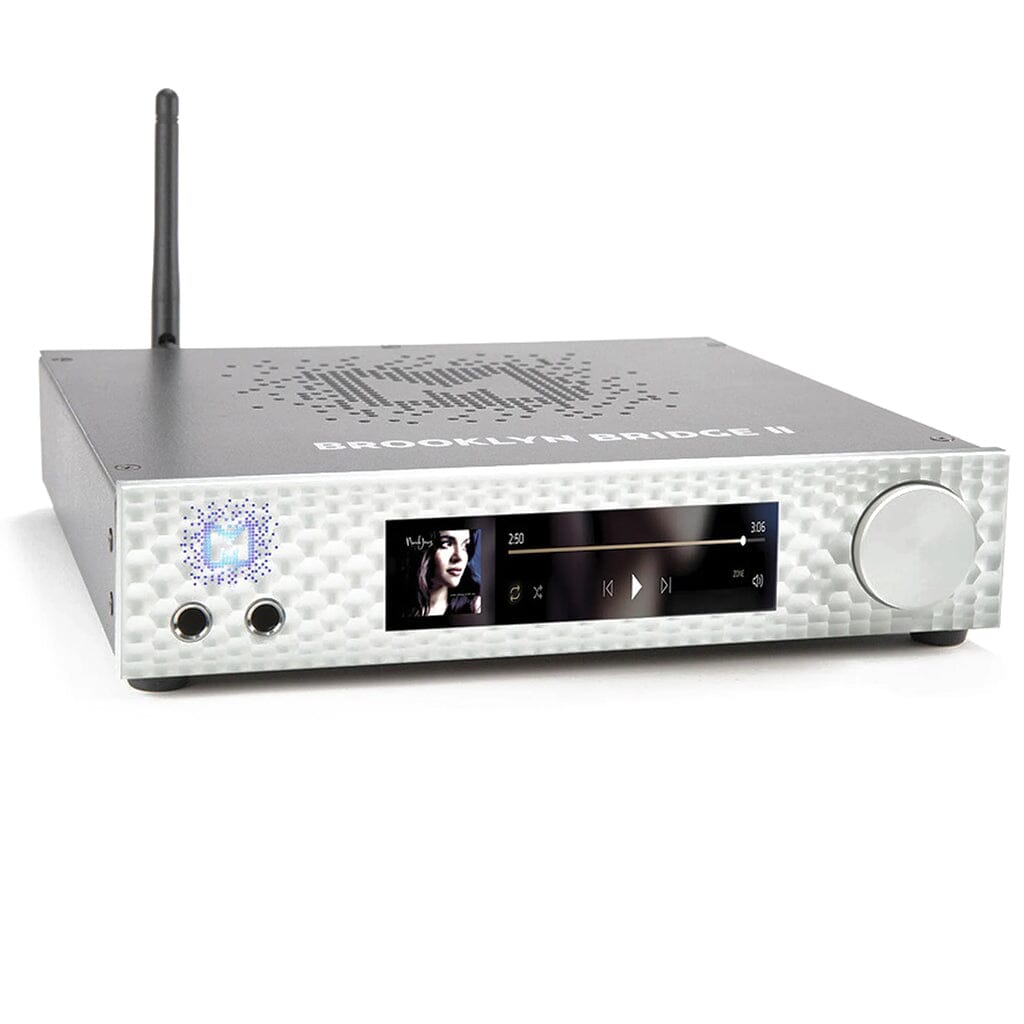 The Mytek Digital Brooklyn Bridge II is a silver hi-fi network streamer, DAC, amp, and pre-amp with ROON Core. It features a digital display for music playback, large right-side knob, rear wireless antenna, and "BROOKLYN BRIDGE II" on top.