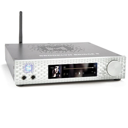 The Mytek Digital Brooklyn Bridge II is a silver hi-fi network streamer, DAC, amp, and pre-amp with ROON Core. It features a digital display for music playback, large right-side knob, rear wireless antenna, and "BROOKLYN BRIDGE II" on top.