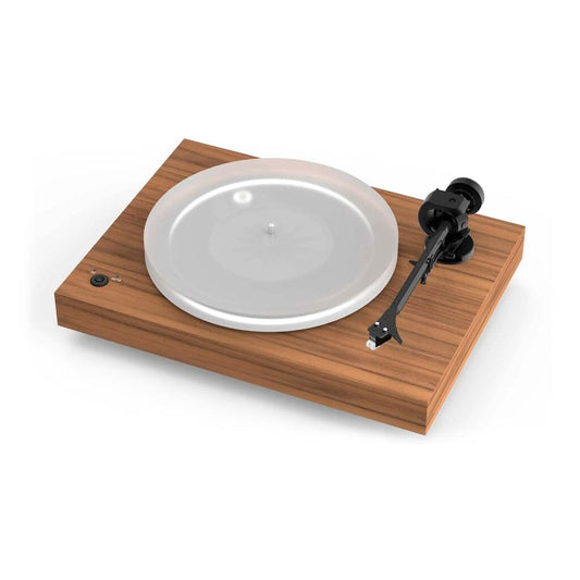 A modern turntable with a satin walnut wooden base, transparent platter, and black tonearm, shown against a white background. The Pro-Ject Audio Systems X2 B Turntable – Satin Walnut is an open box clearance model featuring balanced phono connectivity for superior sound quality and comes equipped with a Sumiko Rainier cartridge for exceptional audio performance.