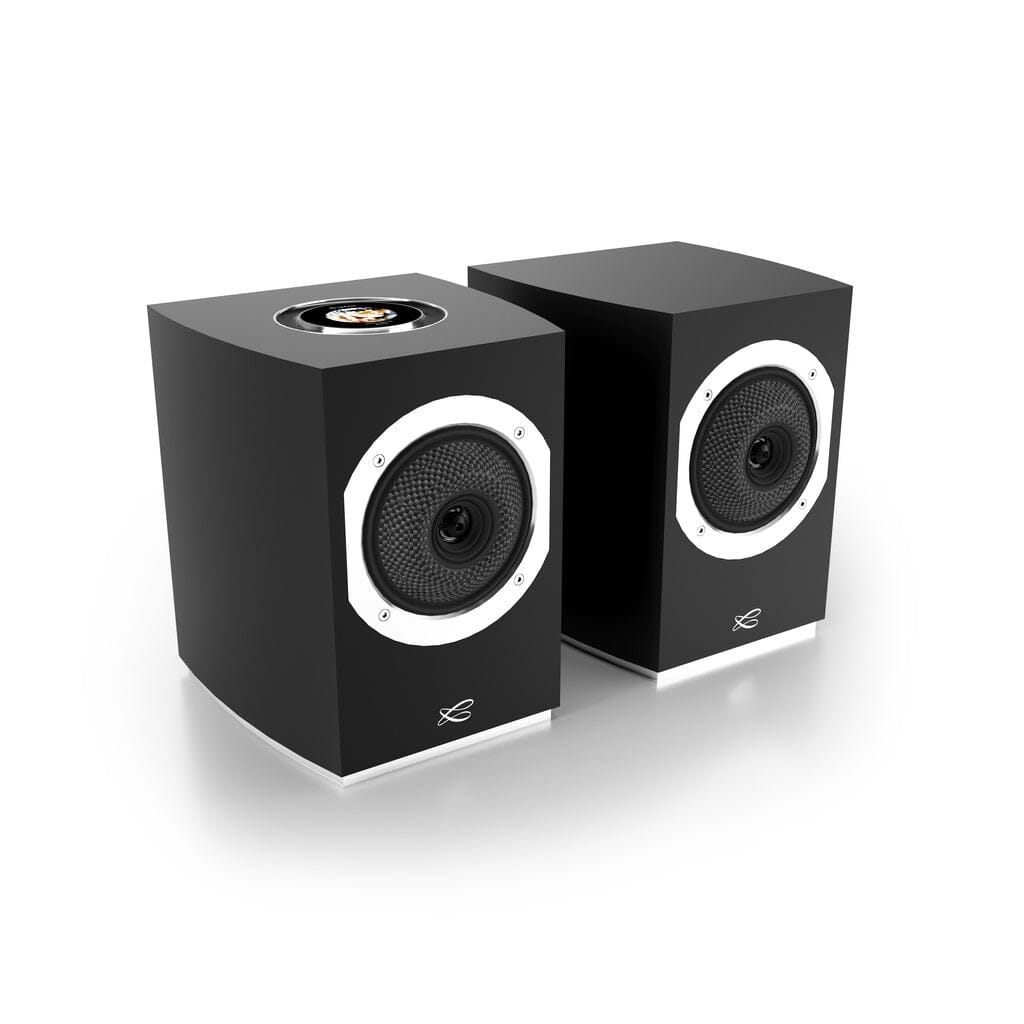 The Cabasse Rialto Wireless Powered Bookshelf Speakers (Pair) by Cabasse feature a sleek black design with white circular accents, mesh fronts, and a top control dial for high-fidelity sound, displayed side by side on a reflective white surface.