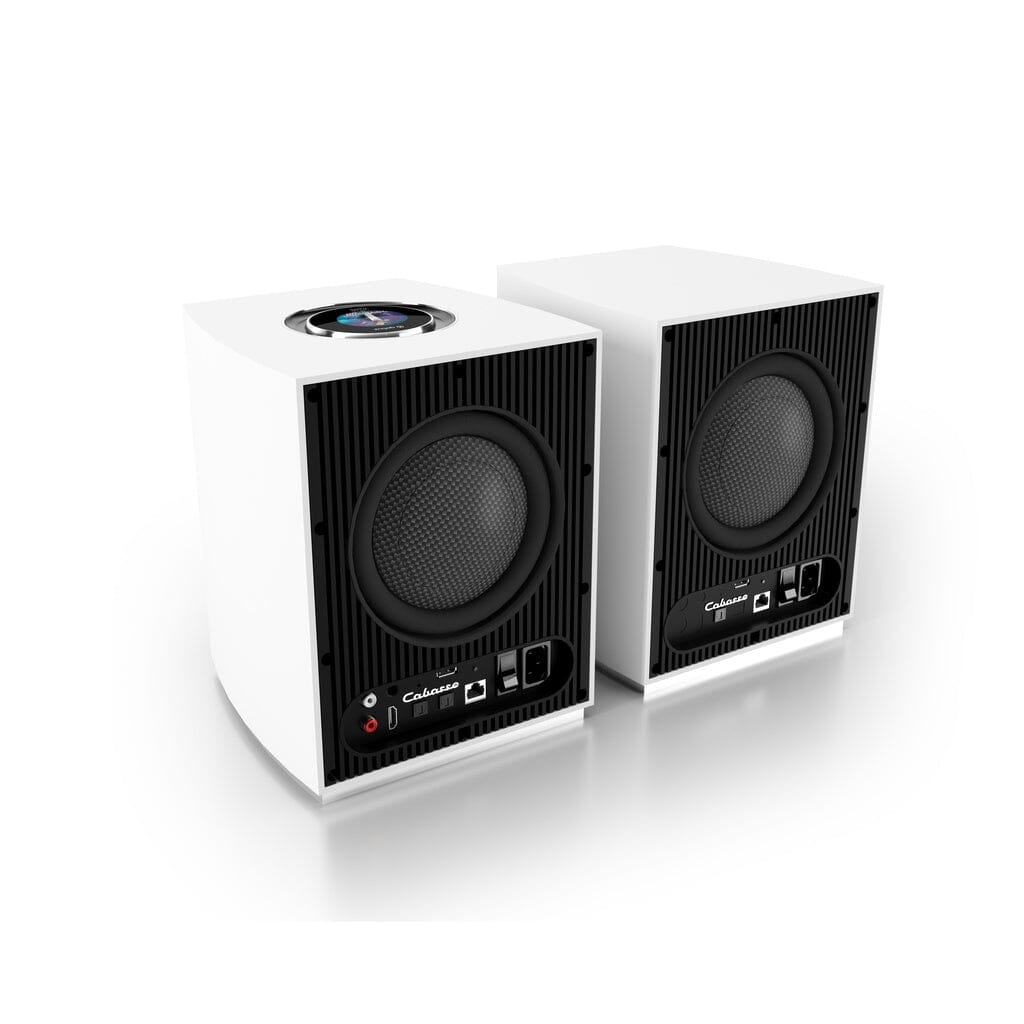 The Cabasse Rialto Wireless Powered Bookshelf Speaker pair features white cabinets with black front panels and visible round drivers, displaying control buttons, input ports, and Cabasse branding for premium hi-fi sound on any surface.