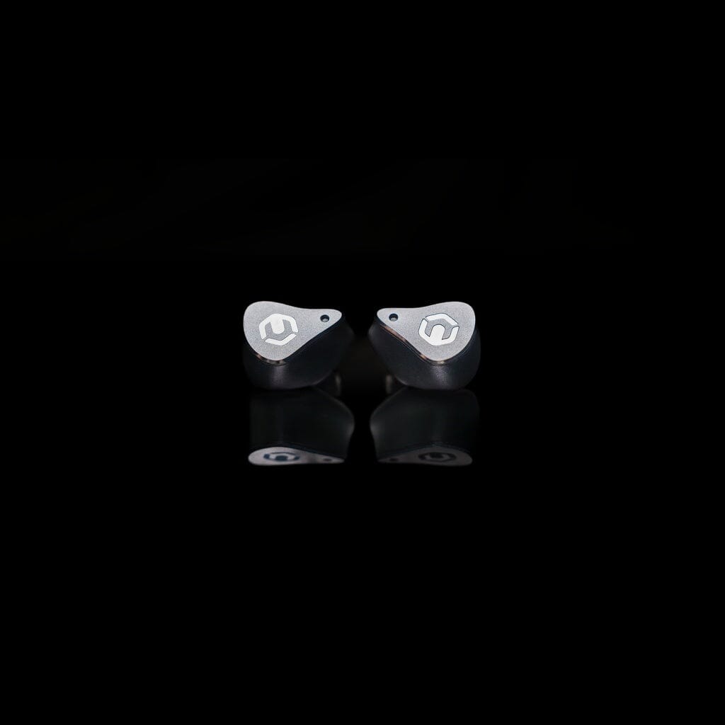 A pair of CrinEar Reference In-Ear Headphones by CrinEar, featuring a sleek metallic finish and stylized logos, are displayed side by side on a black background with a crisp reflection, highlighting their tonal accuracy.