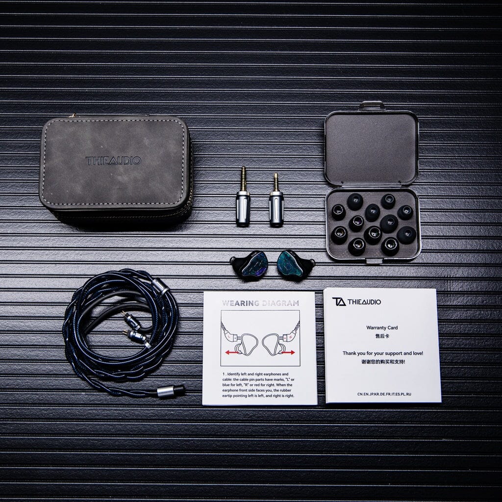 The Thieaudio Hype 4 MK2 In-Ear Headphones set includes detachable cables, multiple ear tips, a carrying case, a warranty card, a user manual, and two audio adapters—all neatly displayed on a textured black surface.